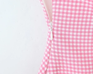 Macro detail of side invisible zipper closure on pink and white plaid fabric dress