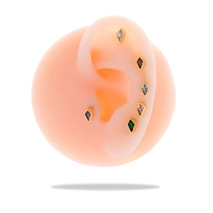 Detailed view of six gold diamond-shaped studs with colorful zircons on a silicone ear model