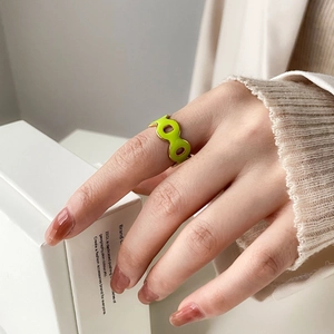 Close-up of green enamel and gold geometric ring with infinity-shaped circular cutouts