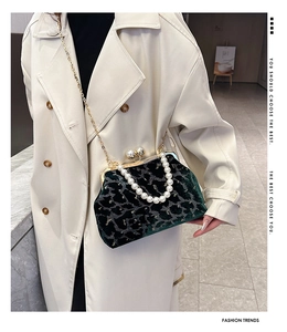 Detailed close-up of dark green velvet shell bag with pearl handle and golden chain strap