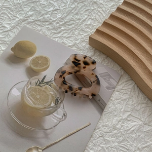 Detailed close-up of tortoise shell pattern hair claw clip on aesthetic background