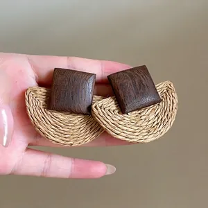 Detail showing the hand-woven raffia and walnut wood texture of the bohemian earrings
