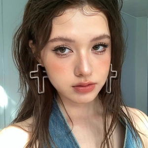 Close-up of minimalist silver hollow cross earrings worn by a model in natural light
