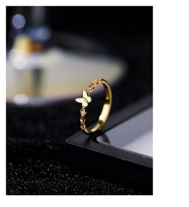 Macro detail of golden braided silver ring featuring a zircon butterfly design