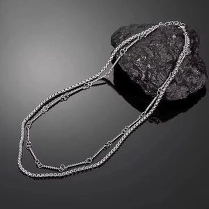 Minimalist double-layered silver necklace with bamboo joints on a dark reflective surface