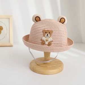 Close-up of pink children straw hat featuring plush bear ears and embroidery detail