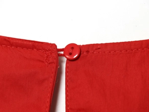 Gros plan d'une robe midi rouge montrant la texture tissée et les boutons assortis