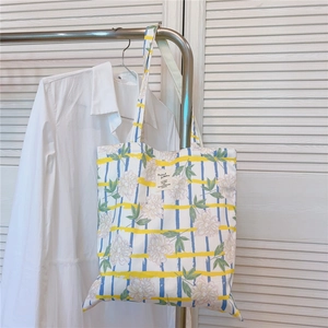 Détail d'un sac cabas en toile à fleurs suspendu dans un décor décontracté et épuré