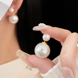 Macro shot of double white pearl stud earring with golden metal post showing fine details