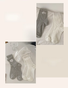 Detail of ribbed knit crew socks featuring heart embroidery in grey and off-white colors