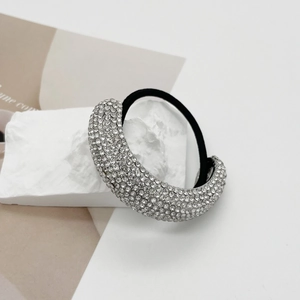 Detailed macro view of sparkling rhinestone hair tie displayed on a white mineral stone