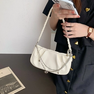 Detail of white pleated cloud bag with woven handle, metal chain, and heart pendant
