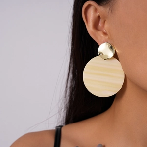 Detail of female model wearing round gold and beige striped acrylic drop earrings