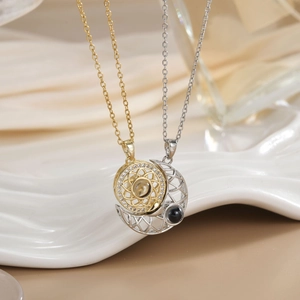 Detailed view of interlocking gold sun and silver moon necklaces on ceramic display