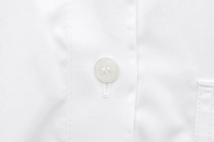Detailed close-up of white resin button and twill fabric texture on a casual shirt