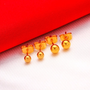 Set of four pairs of polished gold-plated ball stud earrings on a vibrant red background