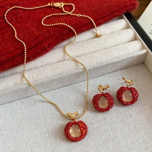 Detail view of red resin apple pendant necklace and matching stud earrings set