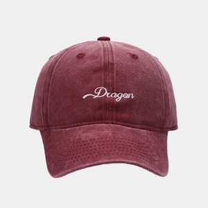 Macro shot of embroidered Dragon logo on vintage washed burgundy cotton baseball cap