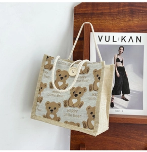 Detail of cute bear tote bag with wooden button closure and rope handle on wooden frame