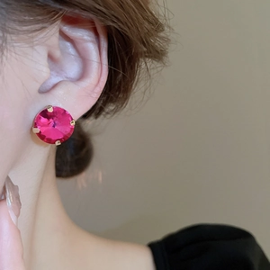 Close-up of elegant rose red crystal stud earrings set in a gold-tone four-prong mount