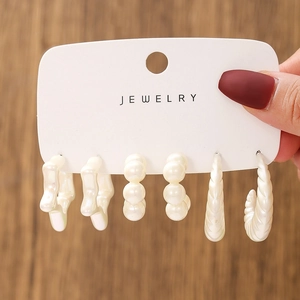 Detailed shot of white geometric acrylic earring set on a display card over wood