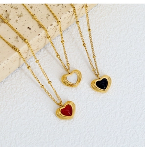 Detail view of heart-shaped pendants in red, white and black on gold-plated chains