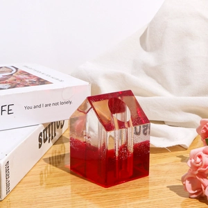 Dettaglio del vaso in resina a forma di casa con bolle su una scrivania di legno