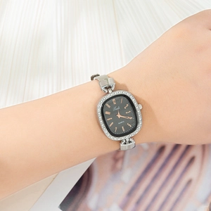 Wrist view of a women's silver mesh watch featuring a black dial with crystal accents
