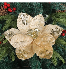 Close-up of golden sequined Christmas flower on green pine branches with red berries
