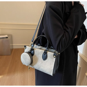 Détail du cabas en toile et cuir noir avec petit porte-monnaie sur manche de veste