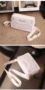 Detailed close-up of white crossbody bag with holographic star patterns and gold hardware