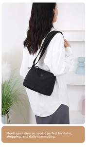 Sac bandoulière moderne en nylon noir avec logo argenté porté par un mannequin