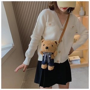 Detail of cute brown plush bear crossbody bag wearing blue denim overalls and bow