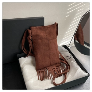 Close-up of caramel suede crossbody bag with fringe detail in a luxury gift box