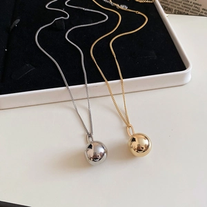 Close-up of gold and silver minimalist ball pendant necklaces on a jewelry tray