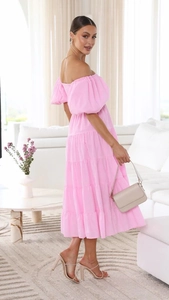 Detailed view of pink off-shoulder bubble sleeve tiered dress in a sunny indoor setting