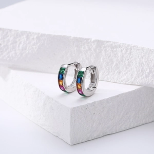 Détail de boucles d'oreilles créoles S925 avec zircons colorés sur une pierre texturée