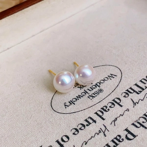 Detailed view of luxury pink button pearl earrings with shiny golden pins on fabric