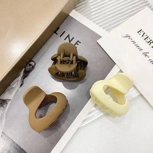 Three-piece set of matte acrylic hair claws in brown and beige on a magazine background
