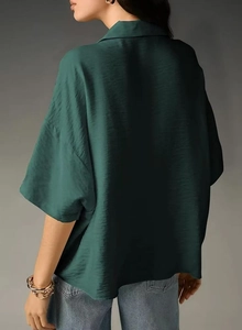 Close-up of dark green textured satin fabric on a short sleeve lapel blouse
