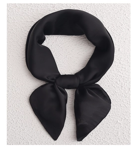 Close-up of a black silk scarf tied in a knot on a white textured background