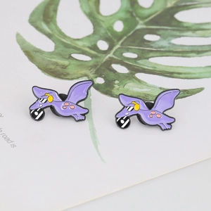 Detail of a purple cartoon dinosaur enamel pin with sunglasses on a leaf background