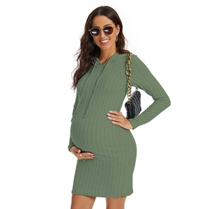 Detailed texture of green knit maternity dress with drawstring hood and long sleeves