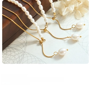 Detail of gold snake chain bracelet with white baroque pearls and adjustable slider clasp