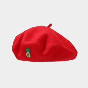 Close-up of red wool beret featuring exquisite yellow and green pineapple embroidery detail