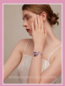 Close-up of S925 silver charm bracelet with pink butterfly enamel pendants on a wrist