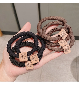 Close-up of elastic scrunchies with cute bear patches in black and brown colors