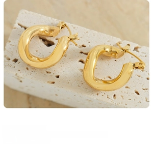 Detail of chunky gold irregular twisted hoop earrings with a high-polish mirror finish