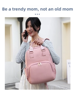 Pink nylon diaper backpack with front zipper pocket shown on a street style model