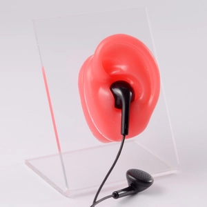 Black wired earphones shown on a red silicone ear model with a clear acrylic stand